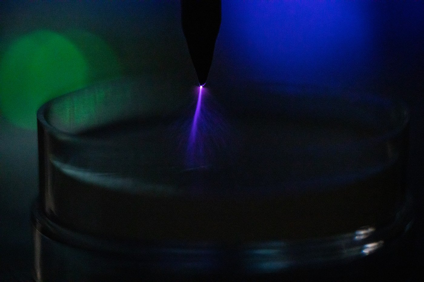 A corona discharge — branching filaments of electric-blue light streaming from a high-voltage point into the surrounding air