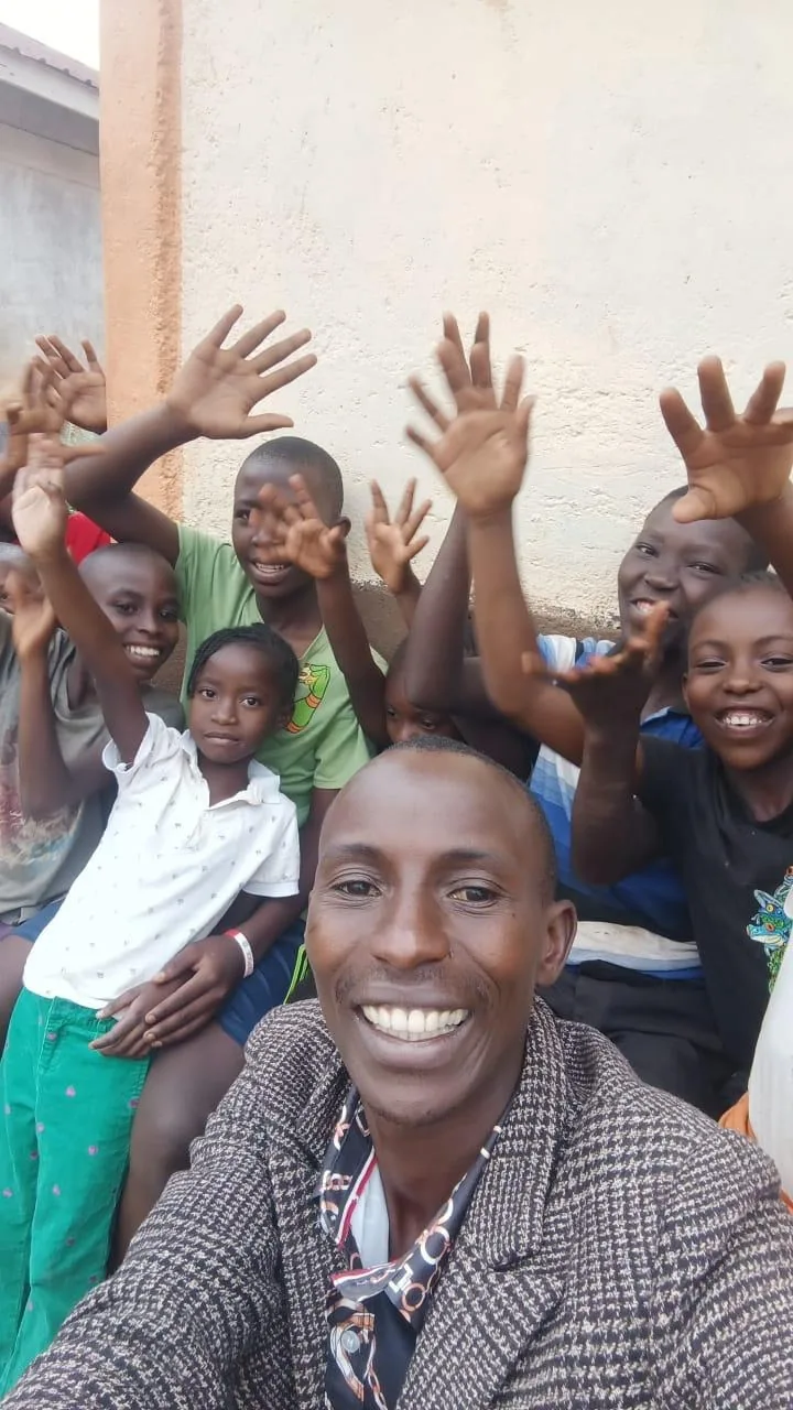 Pastor Dennis smiling with the orphan children he cares for